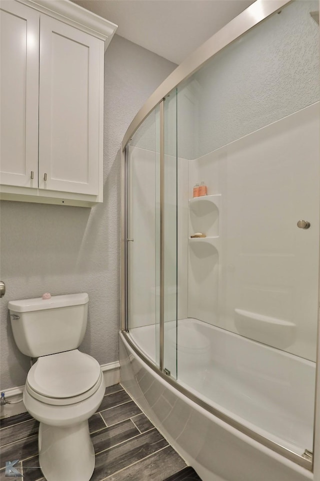 bathroom with toilet and combined bath / shower with glass door