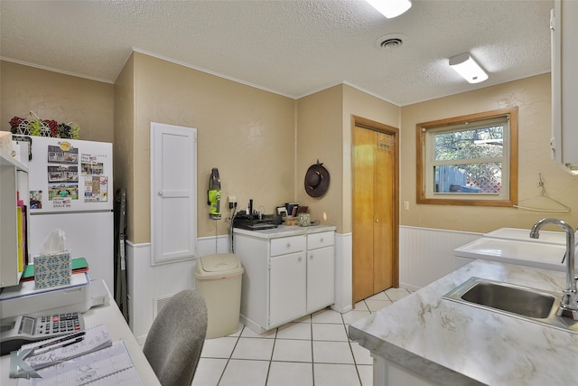 kitchen with a textured ceiling, crown molding, sink, white refrigerator, and white cabinets