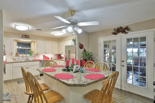 dining room with french doors, light wood-type flooring, a textured ceiling, and ceiling fan