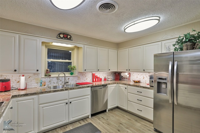 kitchen featuring tasteful backsplash, white cabinetry, sink, and appliances with stainless steel finishes