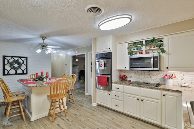 kitchen featuring light stone countertops, appliances with stainless steel finishes, backsplash, and a kitchen breakfast bar