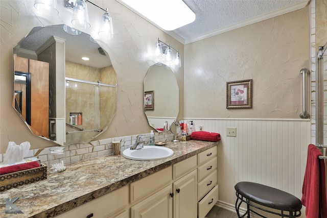 bathroom featuring tasteful backsplash, vanity, a textured ceiling, a shower with door, and crown molding