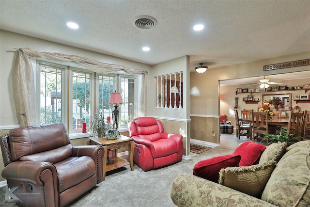 living room with a textured ceiling, light colored carpet, and ceiling fan