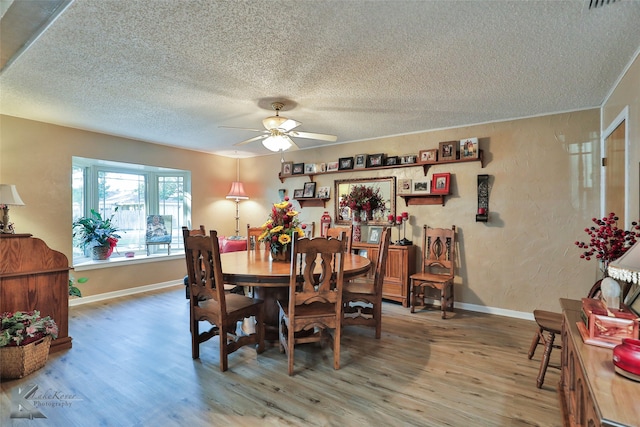 dining space featuring ceiling fan, wood-type flooring, and a textured ceiling