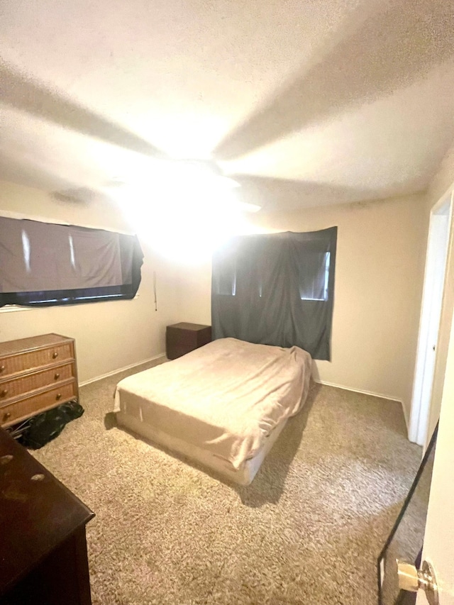 carpeted bedroom featuring ceiling fan and a textured ceiling