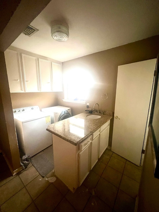 laundry room with washer and dryer, sink, cabinets, and dark tile patterned flooring