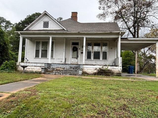 farmhouse with a front lawn and a carport