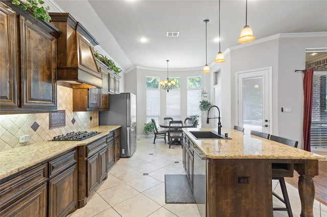 kitchen with pendant lighting, sink, stainless steel appliances, a kitchen breakfast bar, and a center island with sink