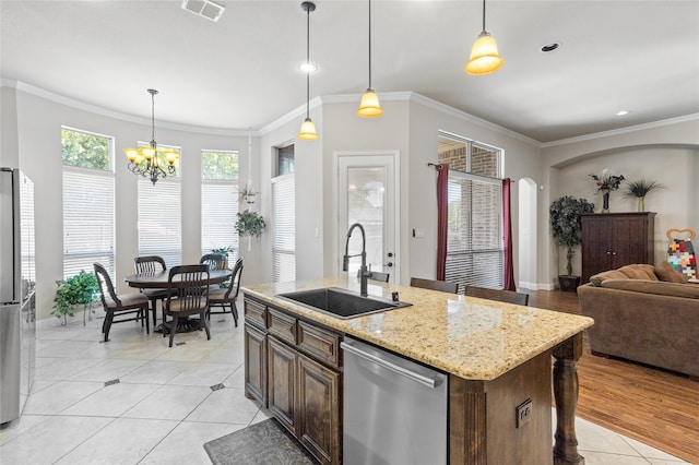 kitchen featuring stainless steel appliances, sink, a kitchen island with sink, and light stone counters