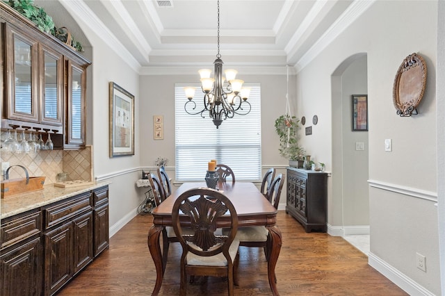 dining room with crown molding, a chandelier, dark hardwood / wood-style flooring, and a tray ceiling