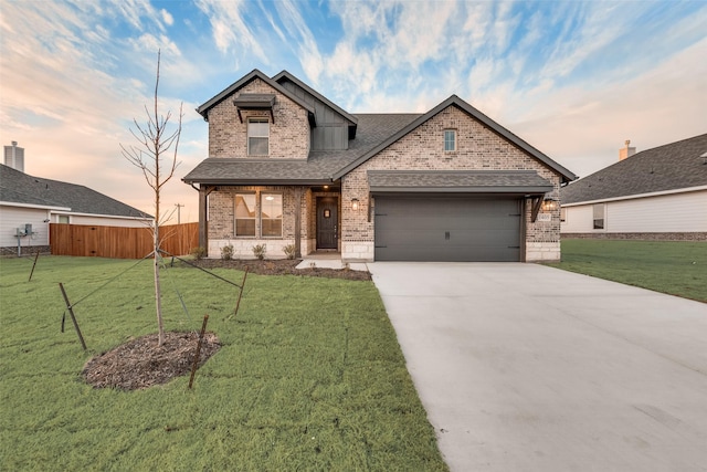 view of front of house featuring brick siding, a yard, roof with shingles, a garage, and driveway