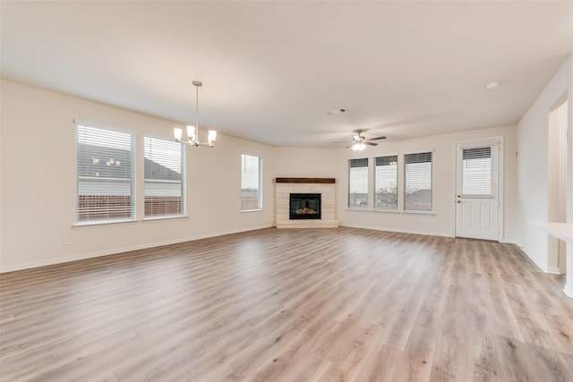 unfurnished living room with light wood-style floors, baseboards, and ceiling fan with notable chandelier