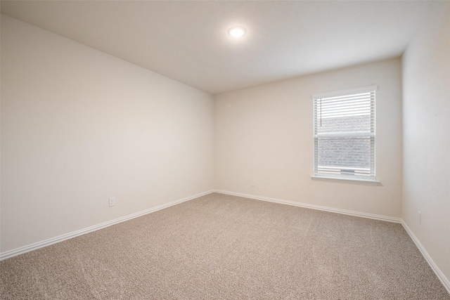 unfurnished room featuring light carpet and baseboards