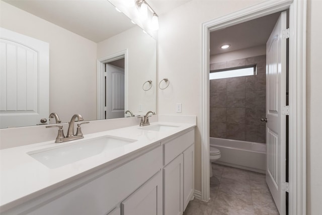 full bath with toilet, double vanity, a sink, and shower / bathtub combination