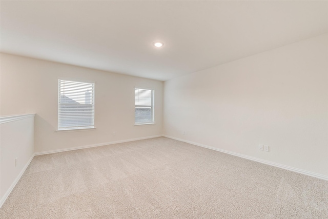 spare room featuring baseboards, recessed lighting, and light colored carpet