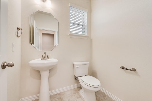 bathroom with a sink, toilet, and baseboards