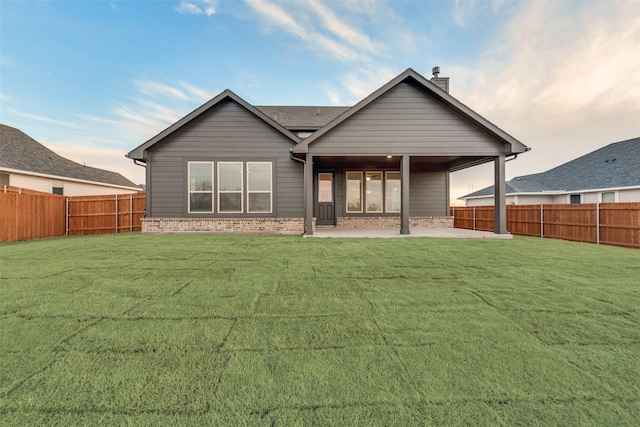 back of property featuring a patio area, a fenced backyard, a yard, and brick siding