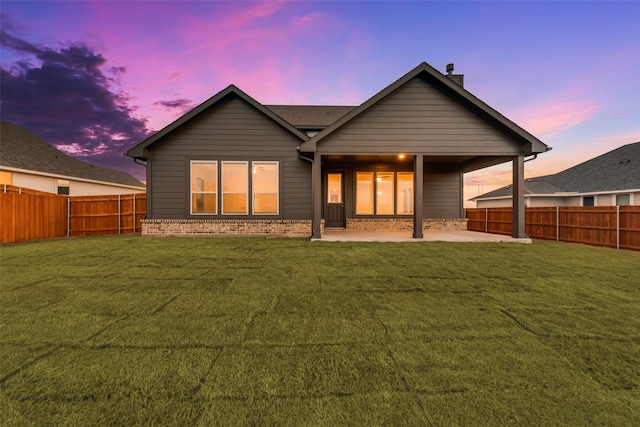 rear view of property featuring brick siding, a lawn, a patio area, and a fenced backyard