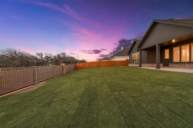 yard at dusk with a fenced backyard and a patio