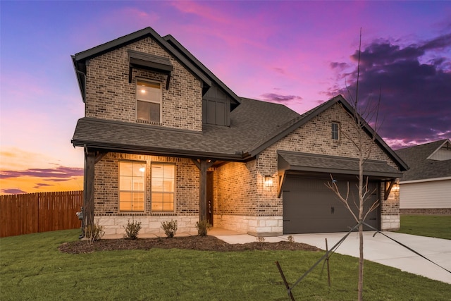 traditional-style house with an attached garage, fence, driveway, roof with shingles, and a front lawn