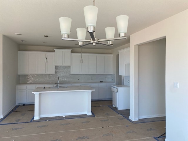 kitchen with a chandelier, decorative light fixtures, white cabinetry, and a kitchen island with sink