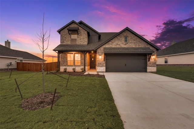 view of front of house featuring concrete driveway, an attached garage, fence, a yard, and brick siding