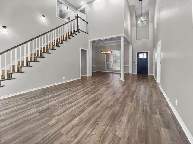 interior space with a high ceiling, decorative columns, an inviting chandelier, and dark hardwood / wood-style floors