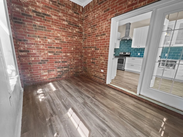 spare room featuring brick wall and hardwood / wood-style flooring