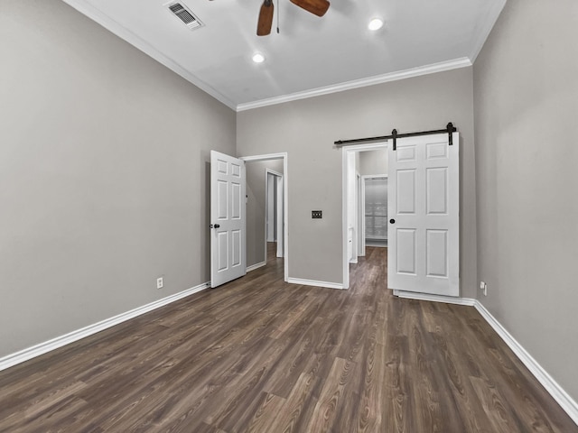 unfurnished bedroom featuring a barn door, ceiling fan, dark hardwood / wood-style flooring, and crown molding