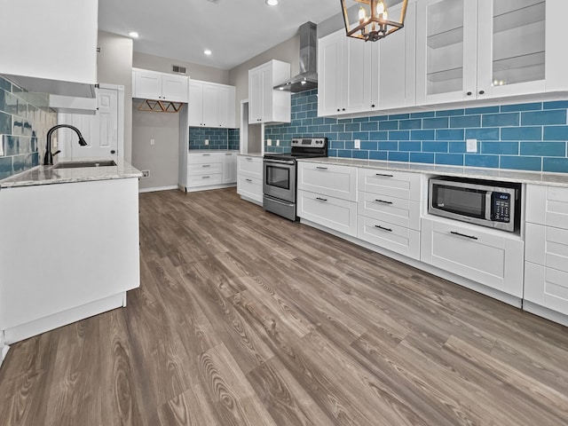 kitchen featuring hardwood / wood-style floors, sink, wall chimney exhaust hood, white cabinetry, and stainless steel appliances