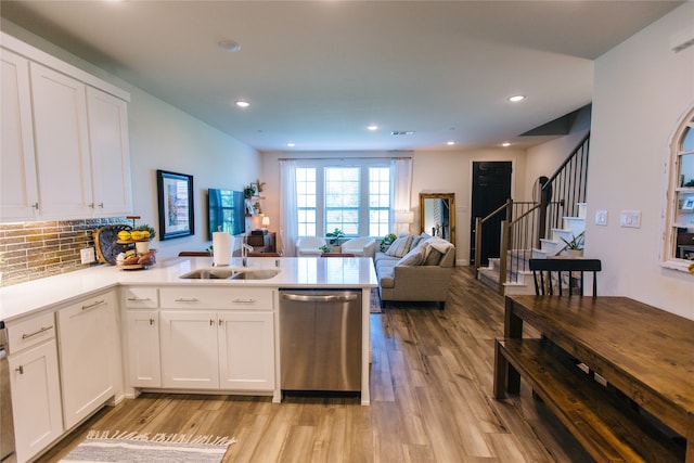 kitchen with stainless steel dishwasher, kitchen peninsula, white cabinetry, and sink