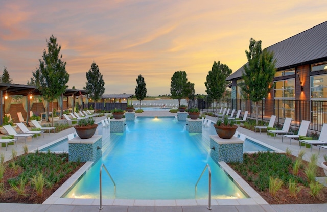 pool at dusk featuring pool water feature