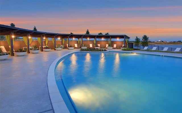 pool at dusk featuring a patio area