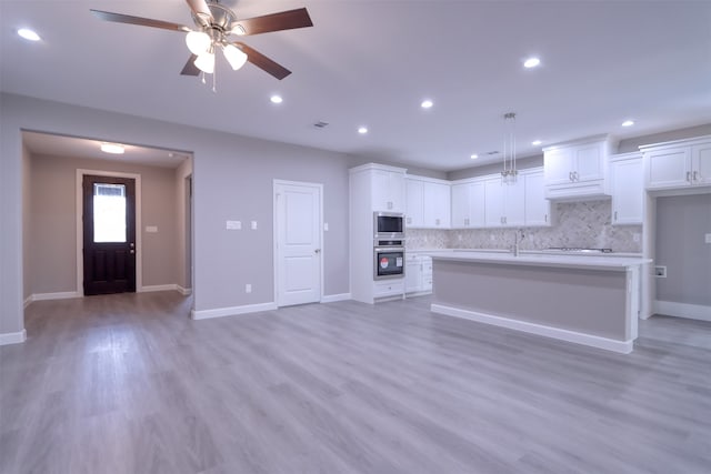 kitchen featuring tasteful backsplash, white cabinetry, stainless steel appliances, and light hardwood / wood-style floors