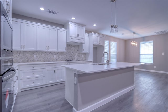 kitchen featuring visible vents, a sink, light countertops, white cabinets, and a notable chandelier