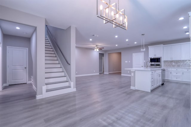 kitchen with light wood-type flooring, recessed lighting, white cabinetry, stainless steel microwave, and tasteful backsplash