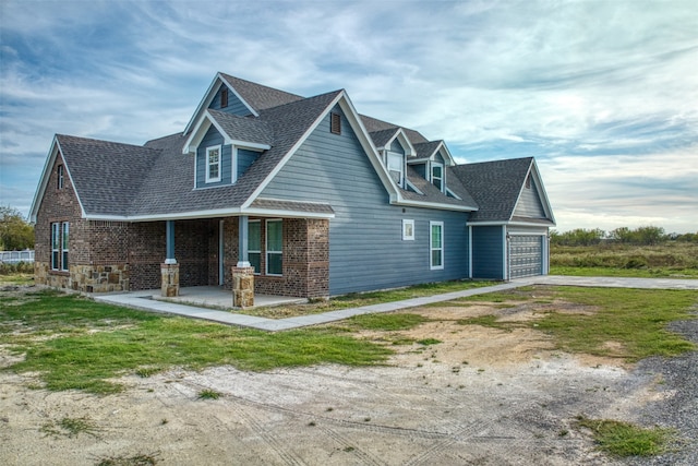 cape cod-style house with covered porch and a garage