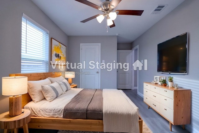 bedroom with a ceiling fan, wood finished floors, visible vents, and baseboards