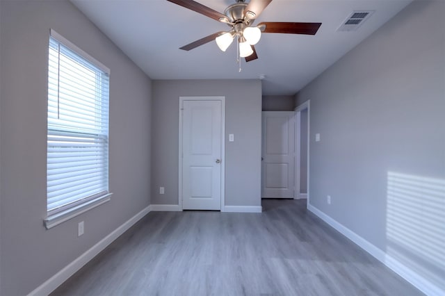 unfurnished bedroom with visible vents, a ceiling fan, baseboards, and wood finished floors