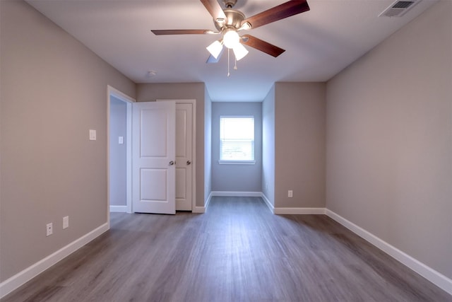 unfurnished bedroom with visible vents, baseboards, wood finished floors, and a ceiling fan