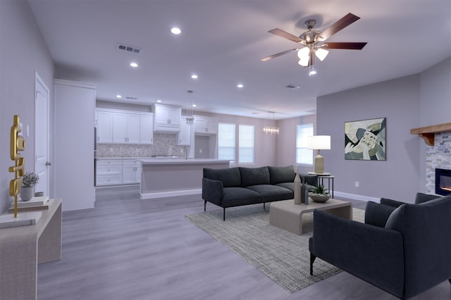 unfurnished living room featuring ceiling fan with notable chandelier, wood-type flooring, and a fireplace