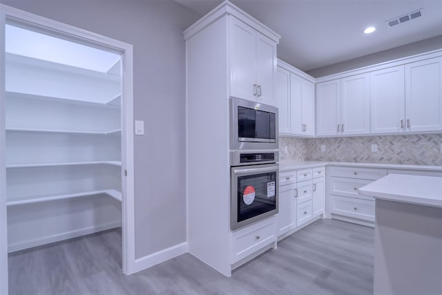 kitchen featuring visible vents, light countertops, stainless steel appliances, light wood-style floors, and white cabinetry