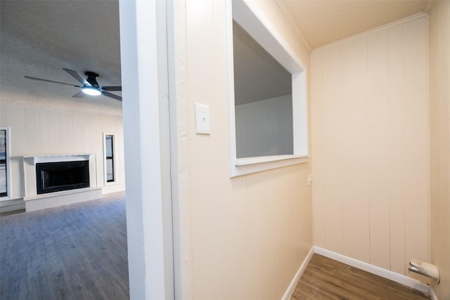 hallway with wooden walls, hardwood / wood-style floors, and a textured ceiling