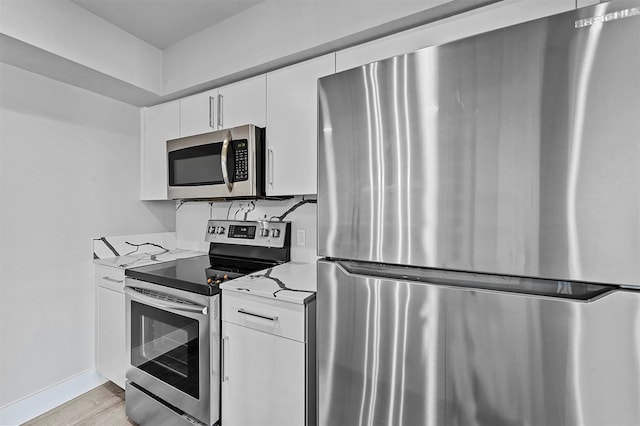 kitchen with white cabinetry, light wood-type flooring, light stone counters, and appliances with stainless steel finishes