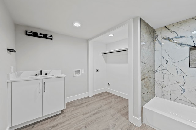 bathroom featuring wood-type flooring, vanity, and tiled shower / bath