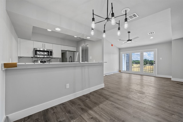 kitchen with white cabinets, ceiling fan with notable chandelier, dark hardwood / wood-style flooring, kitchen peninsula, and stainless steel appliances