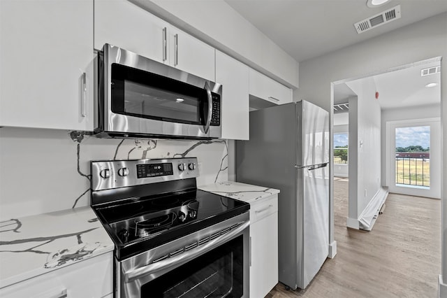 kitchen featuring white cabinets, light stone countertops, light wood-type flooring, and stainless steel appliances