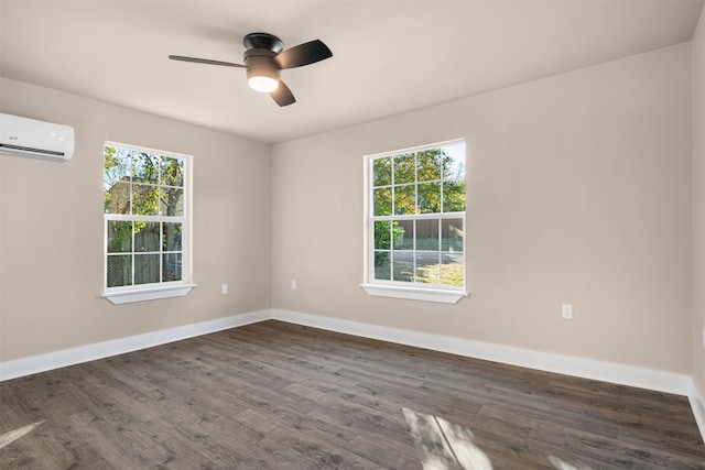 empty room with a wall mounted AC, ceiling fan, plenty of natural light, and dark wood-type flooring