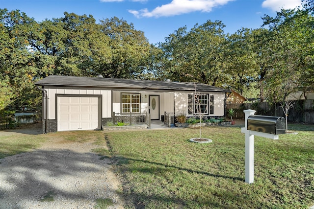 ranch-style home with covered porch, a front yard, and a garage