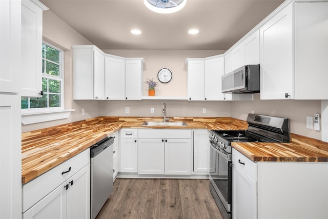 kitchen featuring white cabinets, stainless steel appliances, light hardwood / wood-style flooring, and butcher block counters